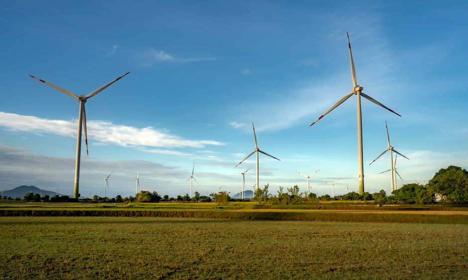 Climate tech investment trends — Wind turbines spinning on green fields under a clear blue sky, symbolizing clean energy.