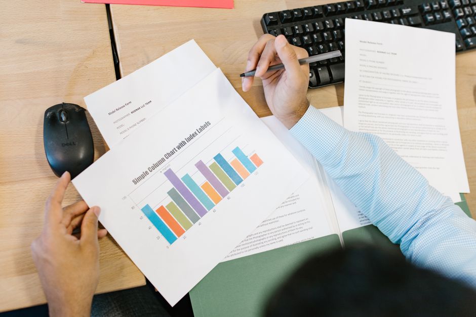 Spot greenwashing in funds — A business analyst reviews a colorful bar chart and documents at a desk, indicating data