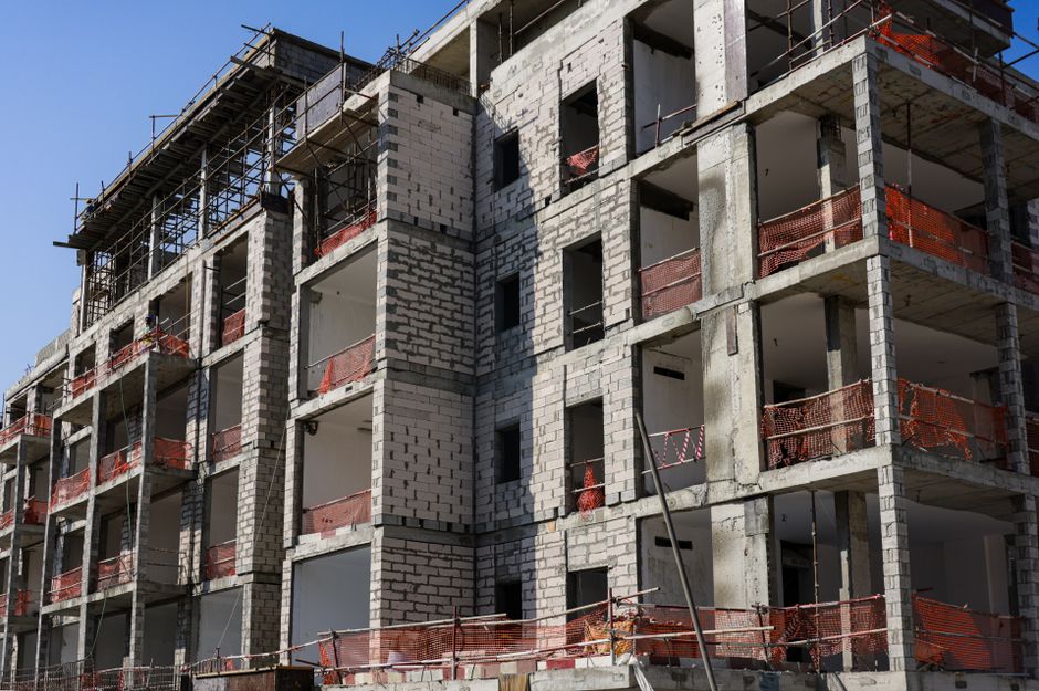 Sustainable real estate REITs — A modern multi-story apartment building under construction with scaffolding and safety
