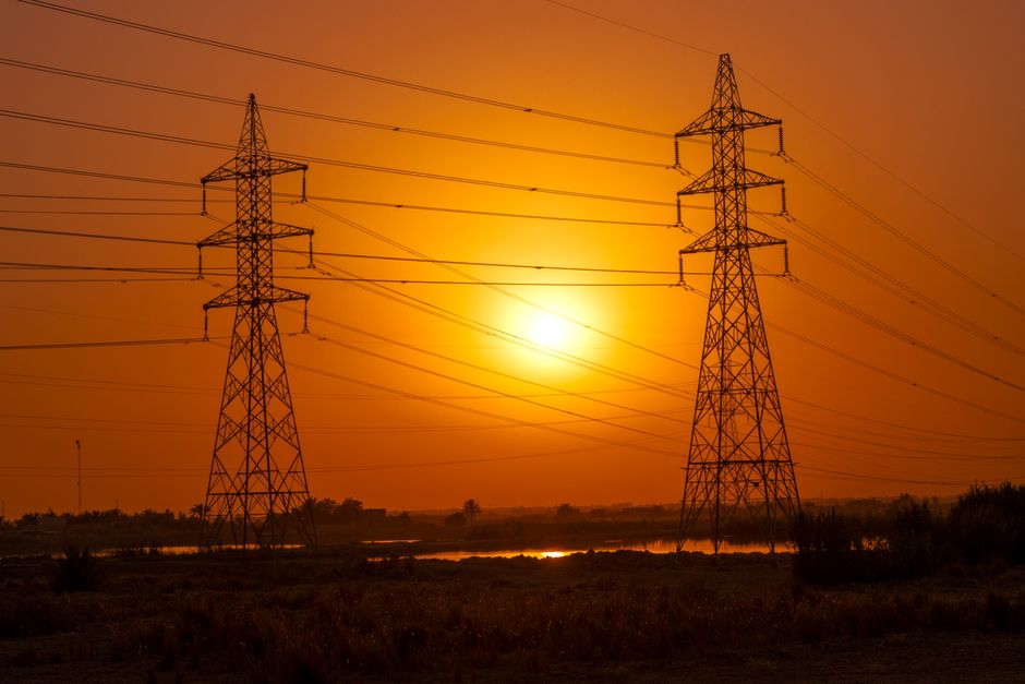 Top renewable energy ETFs — Silhouetted transmission towers under a vibrant sunset in Baghdad, Iraq.